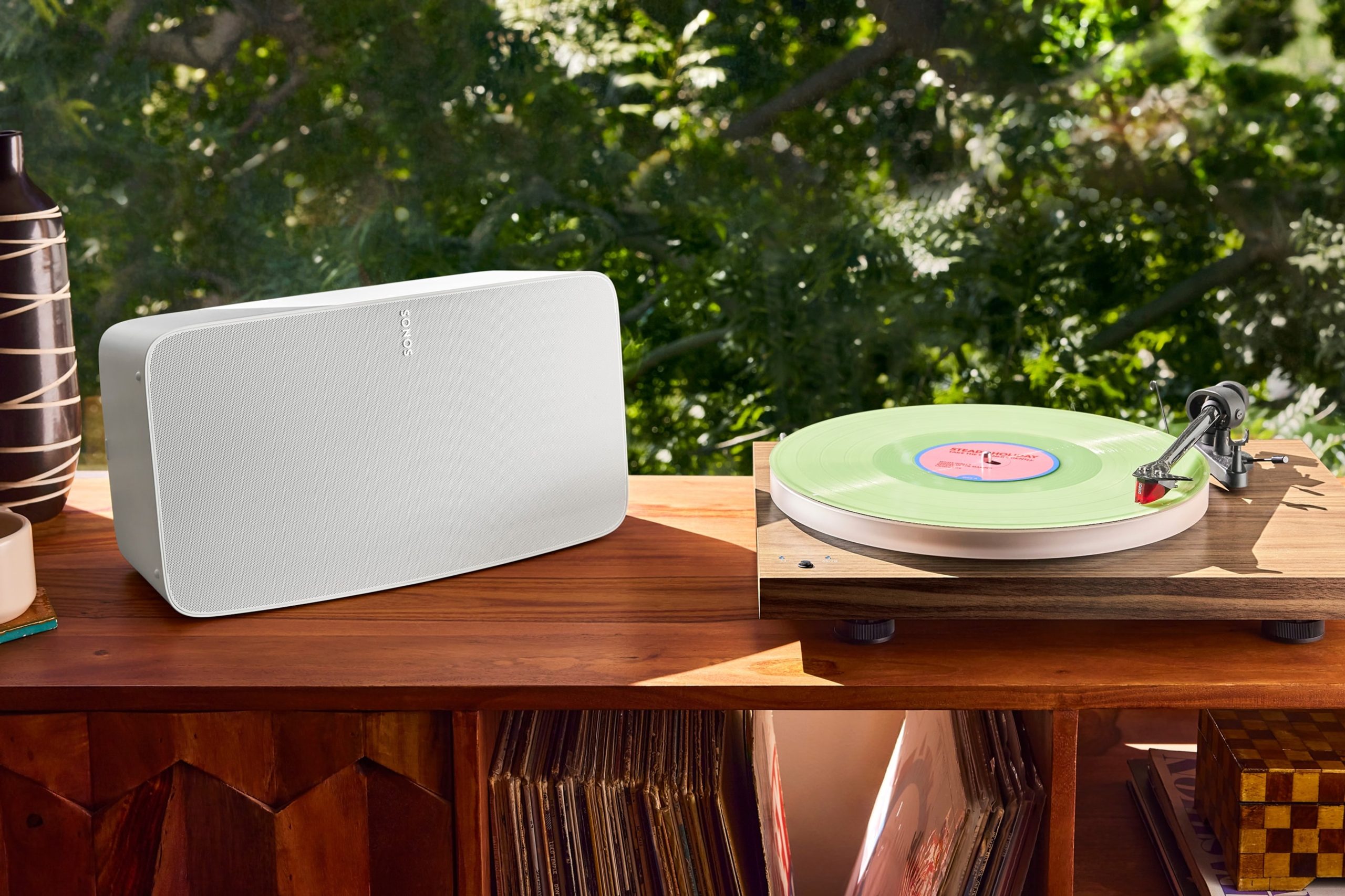 A white Sonos Five speaker on a record cabinet next to a Pro-Ject turntable